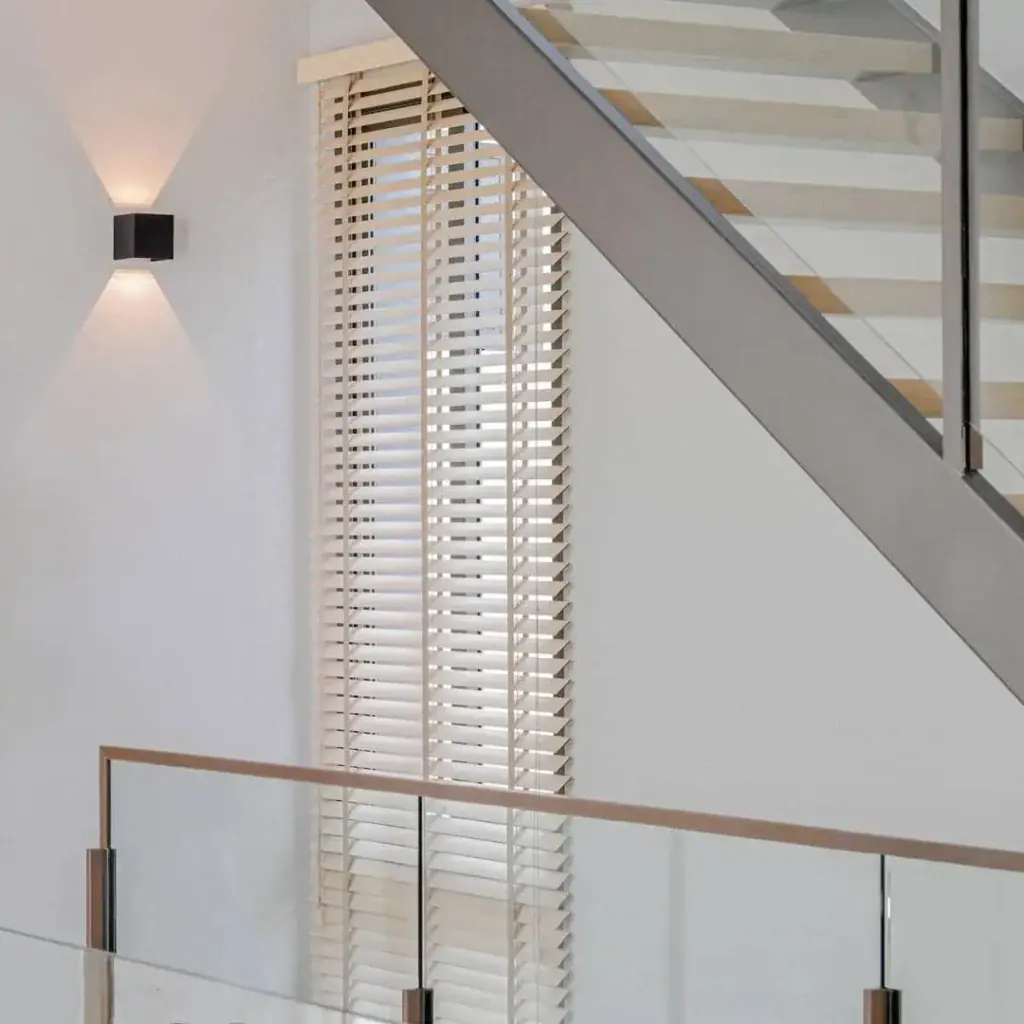 A tall timber blind beside a glass staircase